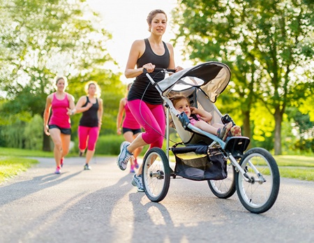 A photo of a mother jogging with stroller after mommy makeover